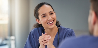 Female in nurses uniform engaged in a work meeting, talking enthusiastically to team member.  