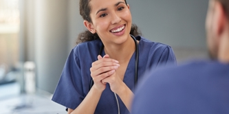 Female in nurses uniform engaged in a work meeting, talking enthusiastically to team member.  
