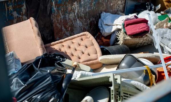 Items of furniture and other bulky waste in a container at a recycling centre.
