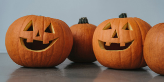 4 pumpkins in a row - 2 carved with faces, 2 uncarved.