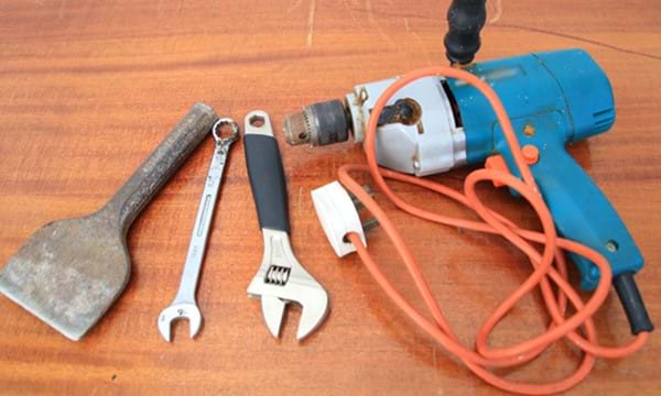 Tools, including a spanner and a powered drill, on a table.