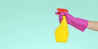 A spray bottle being held by a person wearing a rubber glove.