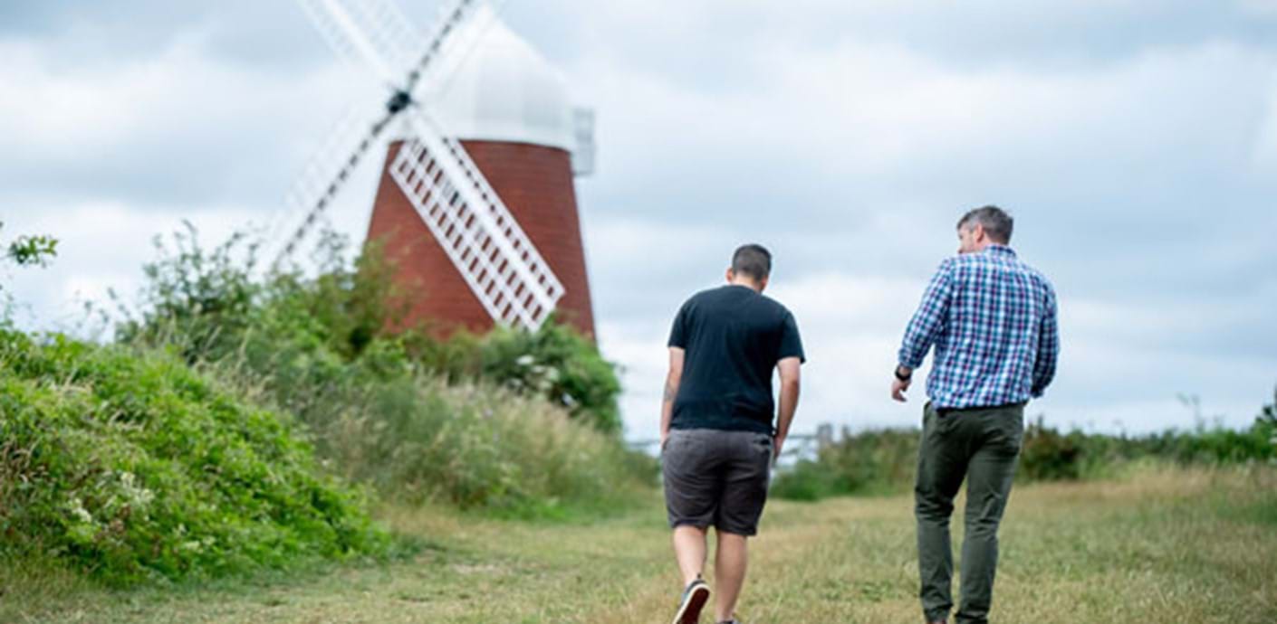 nojs Two men walking up a hill towards a windmill