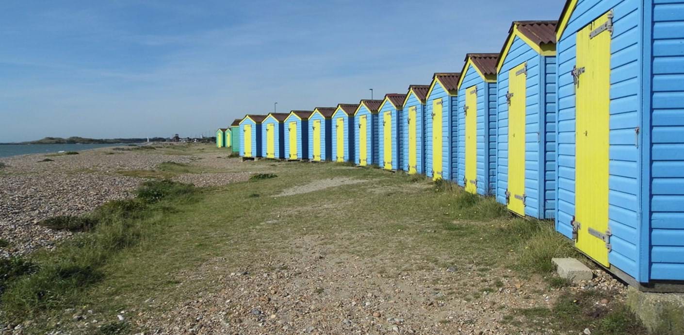nojs Blue and yellow beach huts lined up on a West Sussex beach