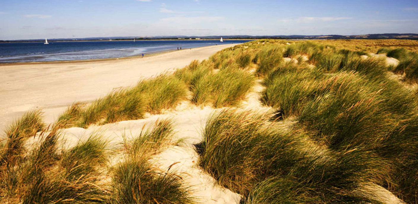 nojs Sand dunes and sandy beach with blue sea in background