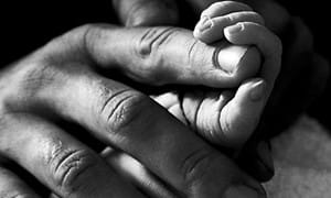 Close up shot of a man holding a baby's hand