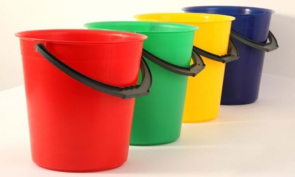 Red, green, yellow and blue plastic buckets in a line