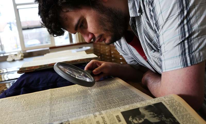 Man looking at a document through a magnifying glass