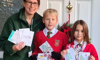 Meals on Wheels staff member along with a boy and girl holding the handmade Christmas cards.