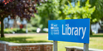An outside view showing a West Sussex Library sign.