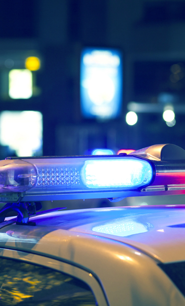 Roof of police car with lights on it parked in a street at night