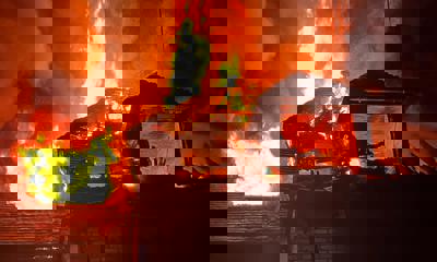 Photo of a house ablaze with flames above the roof.