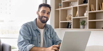 Happy, male sitting at laptop at home