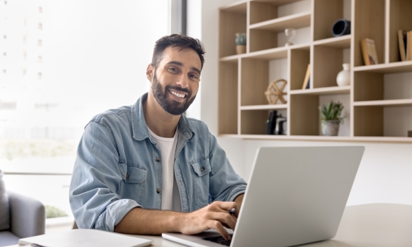 Happy, male sitting at laptop at home