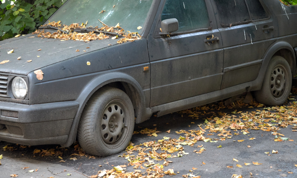 An old black car with a flat tyre.