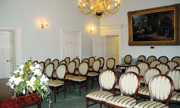 Elegant ceremony room with chairs laid out and large painting in the background