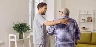 A male carer caring for an elderly man