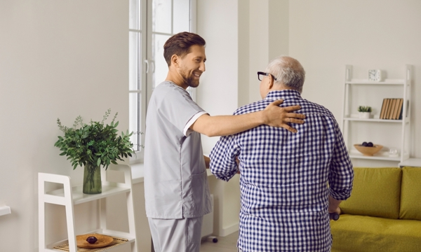 A male carer caring for an elderly man