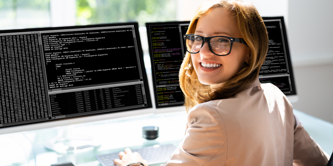 A girl smiling to the camera with a computer screen behind her