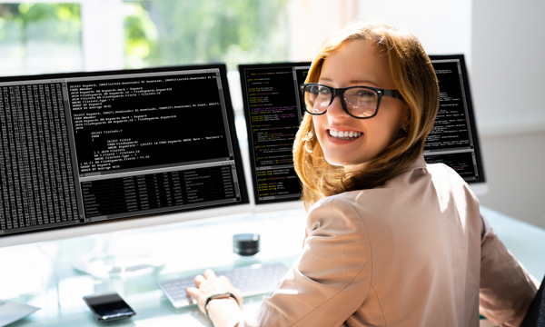 A girl smiling to the camera with a computer screen behind her