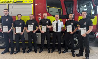 On-call firefighters holding their certificates with Area Manager for Service Delivery, Ady Carter