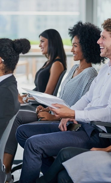 A group of people sitting in chairs in lines enjoying a presentation.