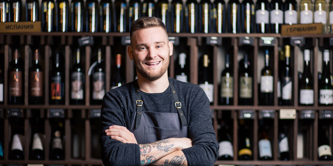 Confident young male sommelier in the wine cellar with arms crossed