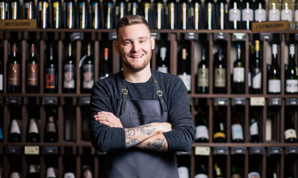 Confident young male sommelier in the wine cellar with arms crossed