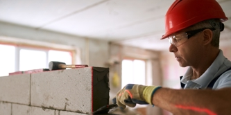 A man in a hard hat laying some bricks