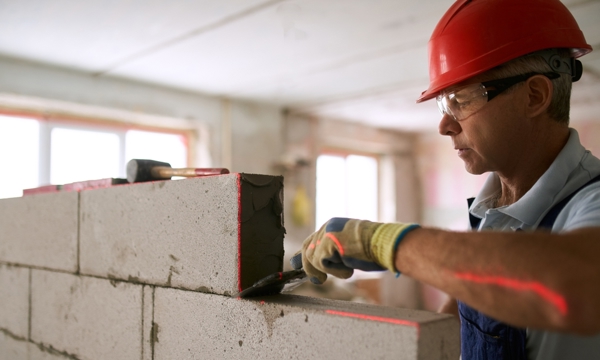A man in a hard hat laying some bricks