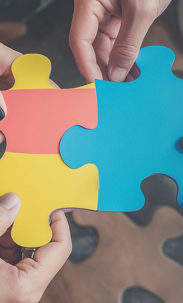 A number of hands holding large coloured jigsaw pieces.
