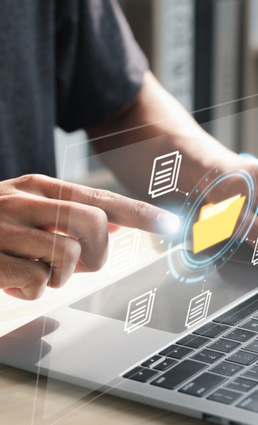 Person using a laptop while pointing at a virtual image of a folder and it's contents.