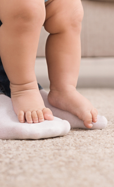 The feet of a young person and a baby.