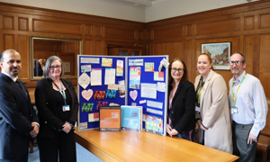 Officers from West Sussex County Council line up alongside Councillor Jacquie Russell, Cabinet Member for Children, Young People and Learning in front of a board displaying items relating to support for young carers.