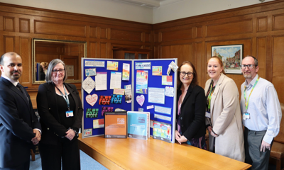 Officers from West Sussex County Council line up alongside Councillor Jacquie Russell, Cabinet Member for Children, Young People and Learning in front of a board displaying items relating to support for young carers.