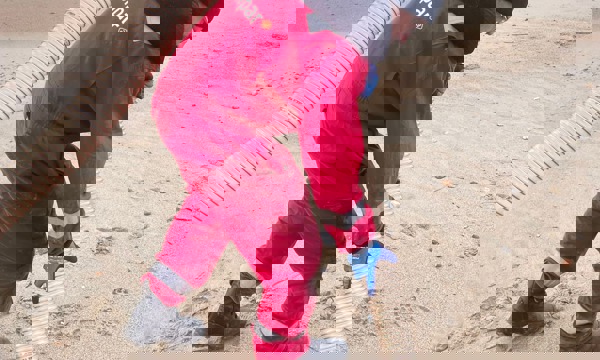 Man with specialist equipment to hoover debris from beach 