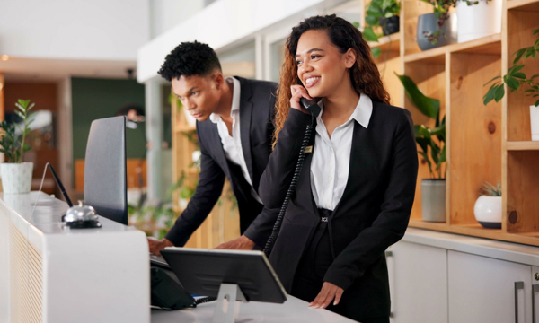 A woman on the phone and a man looking at a computer screen.