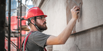 Man, young, caucasian, filing cracks on building.
