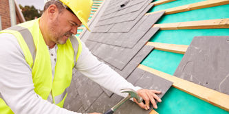 A man in high vis working on a roof