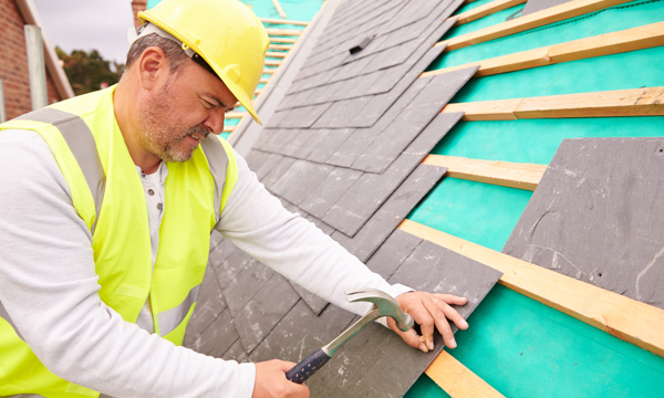 A man in high vis working on a roof