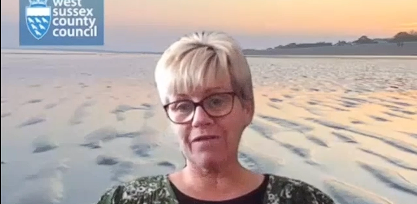 Carla talking to the camera with a superimposed beach background