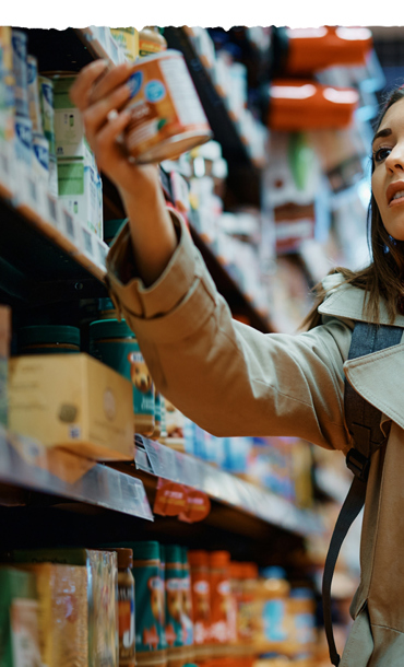 A young woman grabbing a tinned food item while food shopping.