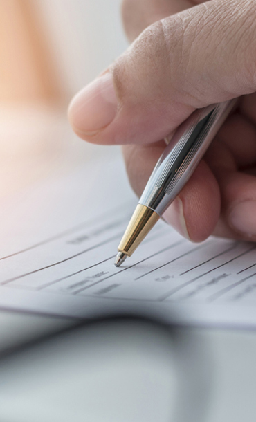 A person completing a paper form with a pen.