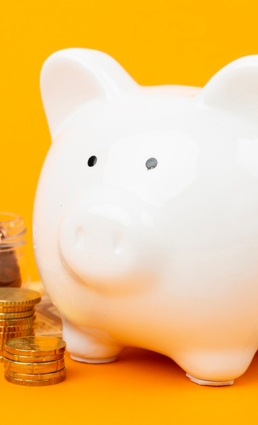 A ceramic piggy bank with a jar, coins and notes on an orange background.