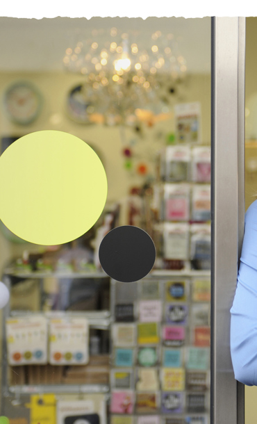 A young female volunteer worker in uniform leaning against a shopfront door.