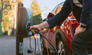 Man plugging a chargepoint cable into a red Electric Vehicle