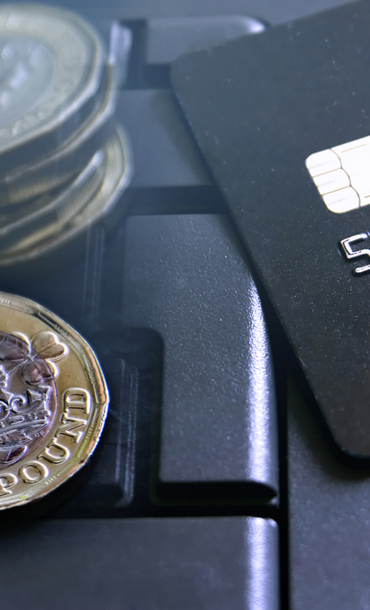 Two small coin stacks and a bank card on a laptop keyboard.