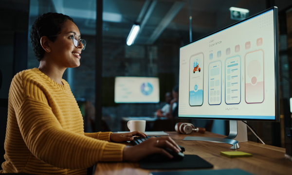 Female, young, Latino, at her desk in front of monitor- happy
