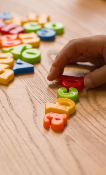Child playing with coloured alphabet shapes.