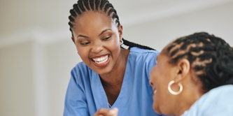 Female patient and female nurse laughing together.